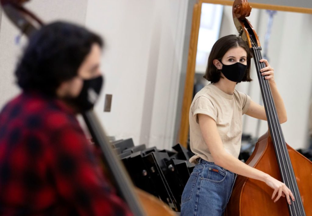 Two students, wearing masks, playing the double bass during LUME rehearsal