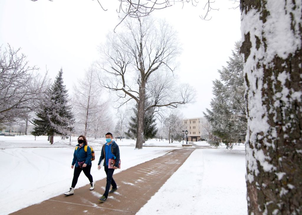 Two students walking across campus during snowy Winter