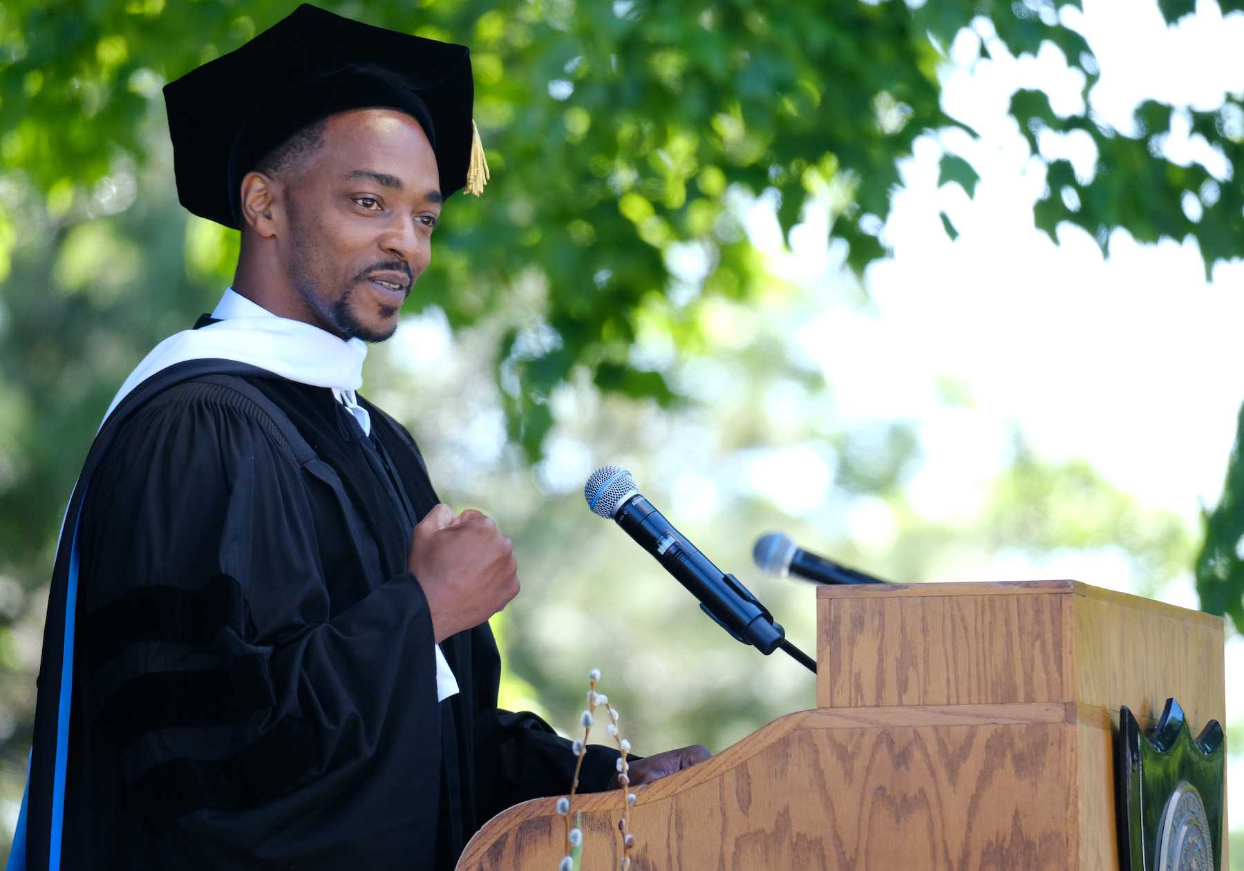 Anthony Mackie gestures with a fist pump as he speaks at the podium during commencement.