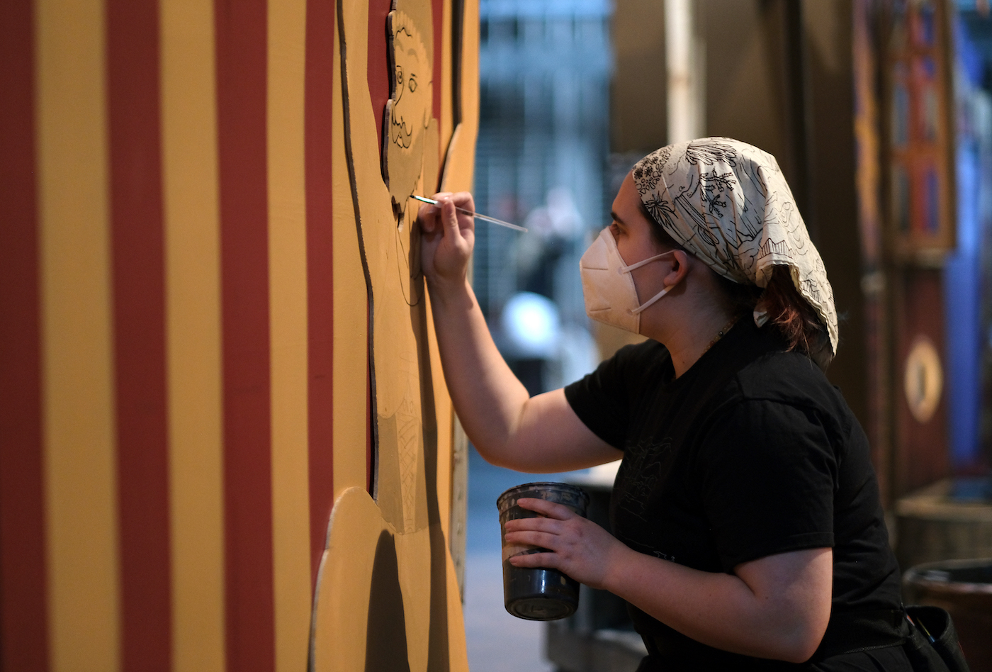 Sophomore August Hendrix paints details on one of the cutouts on the Stansbury stage.
