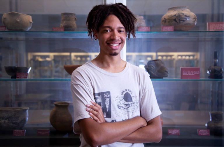 特伦斯·弗里曼 stands in front of a pottery display and smiles at the camera.