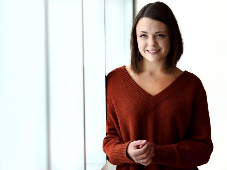 Martha Strawbridge poses against a white backdrop as she wears a red sweater.