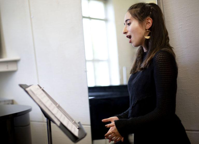 艾米丽奥斯丁 looks at sheet music on a music stand as she sings.