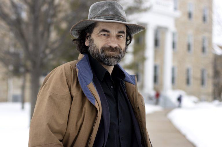 Jake Frederick, wearing a grey, rimmed hat, stands on a snow-covered Main Hall Green.