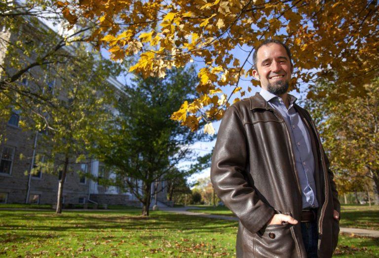 Stefan Debbert smiles at the camera, standing against a backdrop of deciduous trees.