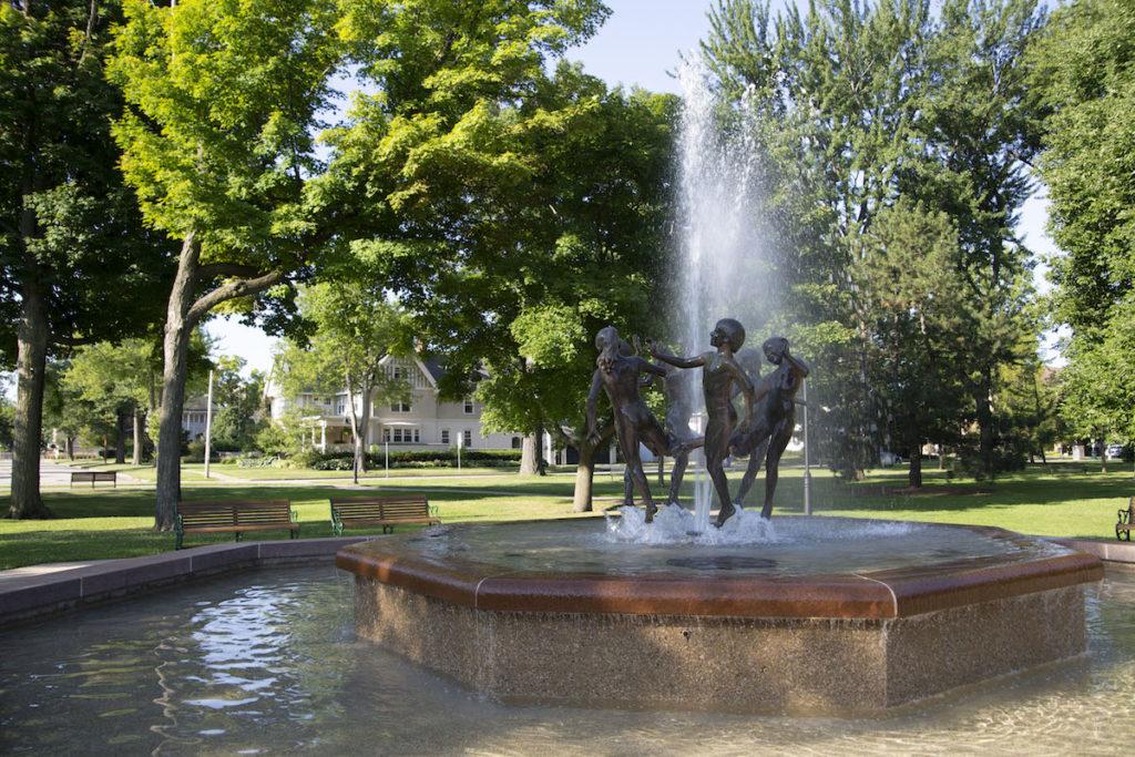 sculpture of kids playing in the middle of a fountain on a sunny day