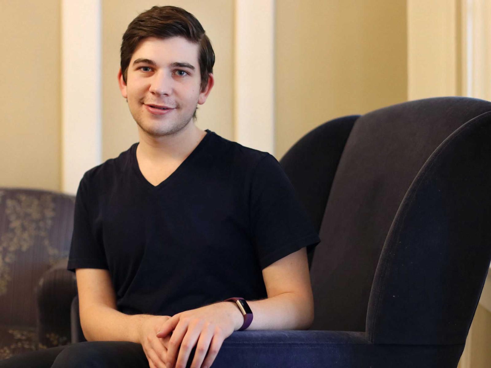 Jason Bernheimer sits in a black chair with his hands resting on the armrest.