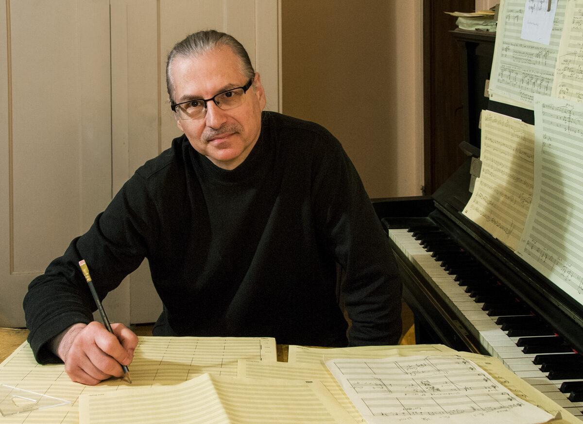 戴夫Rivello at desk with sheet music and a pencil in hand.
