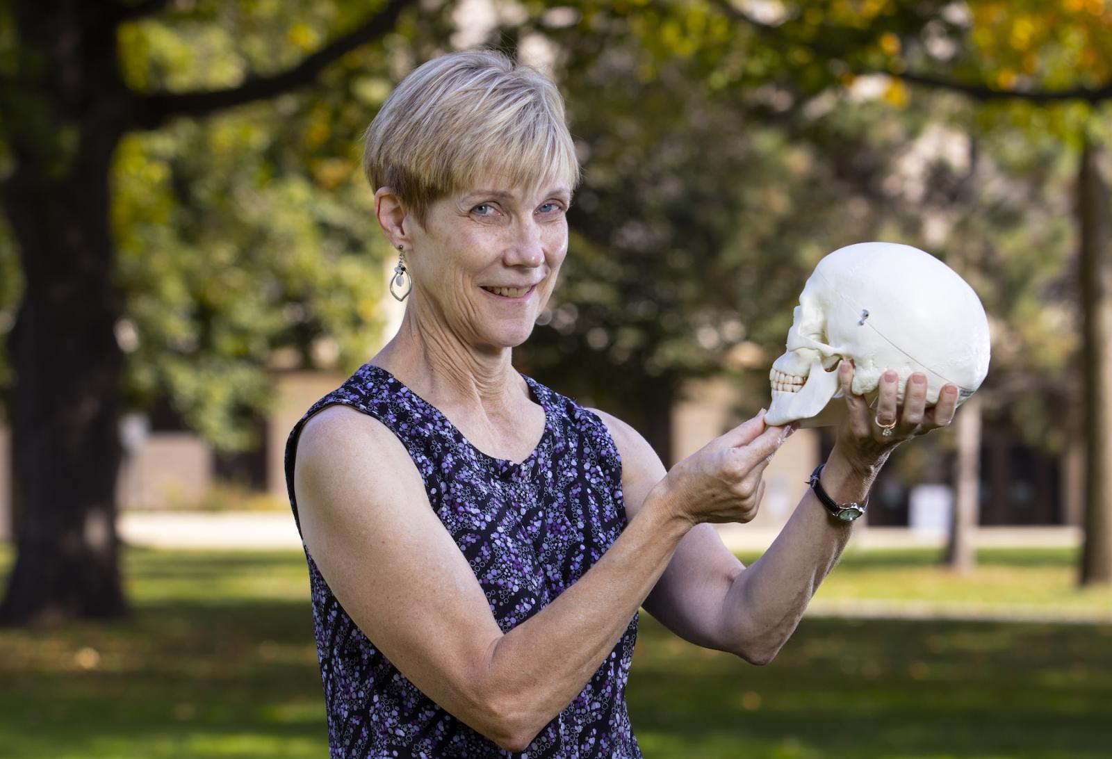Kathy Privatt holds out a fake human skull on Main Hall Green.