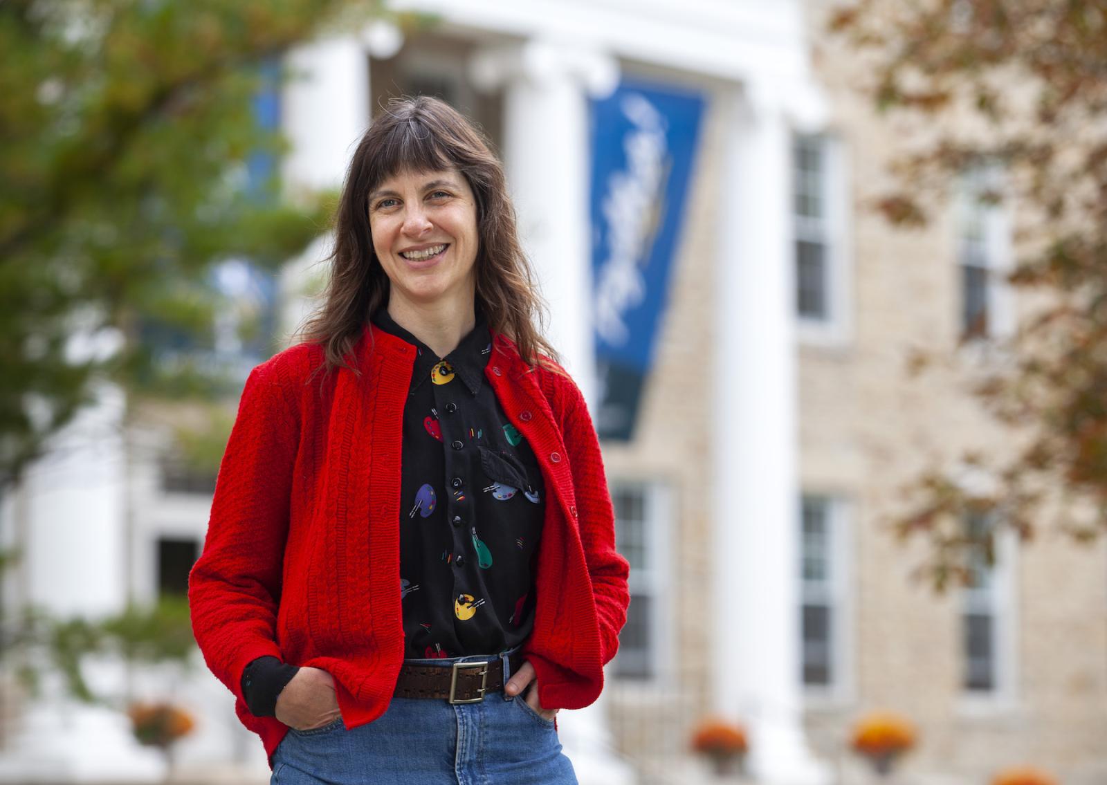 Melissa Range, wearing a red jacket, st和s in front of Main Hall.
