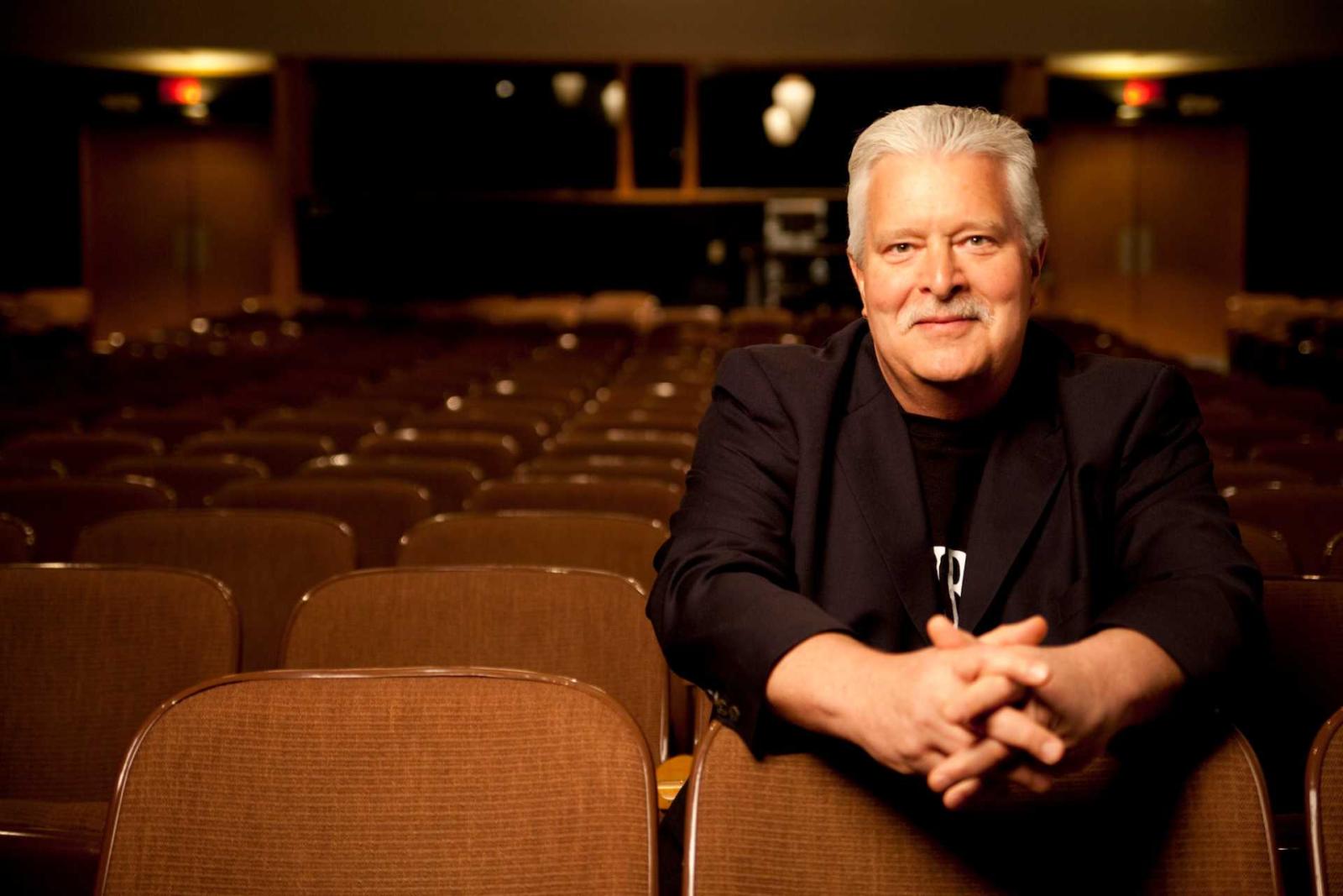 Fred Sturm sitting in an audience seat in an empty auditorium