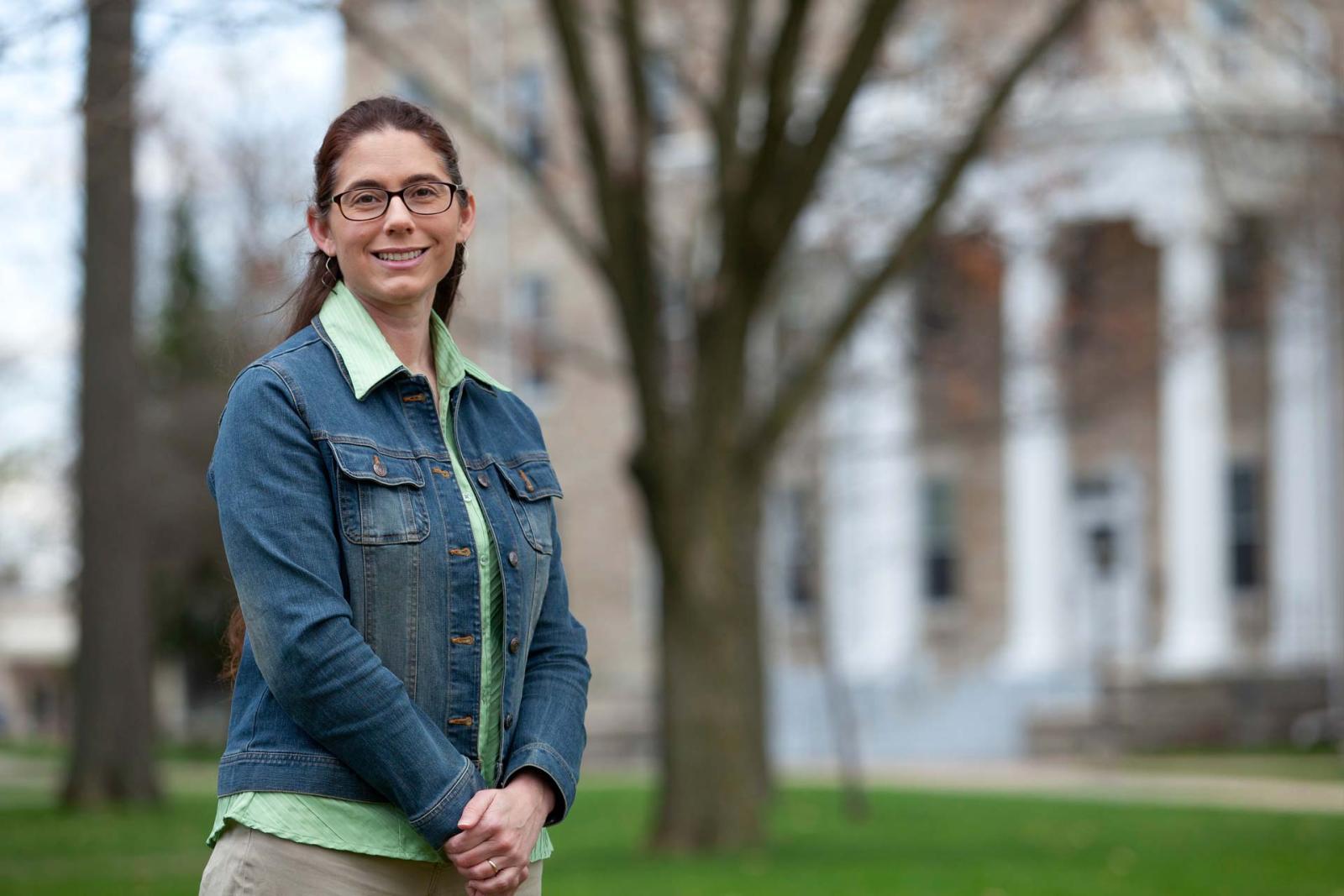 Alyssa Hakes, wearing a denim jacket, smiles at the camera.