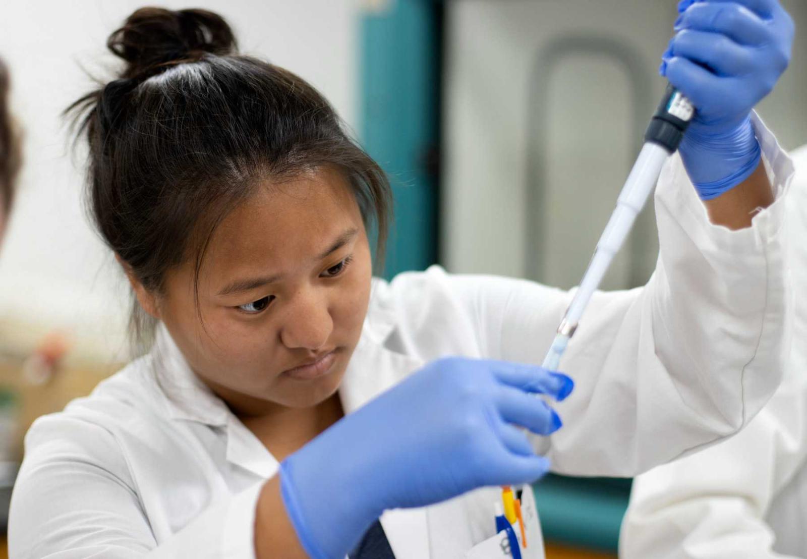 Katie Mahorney wears gloves and a lab coat as she works on research during the summer of 2021.