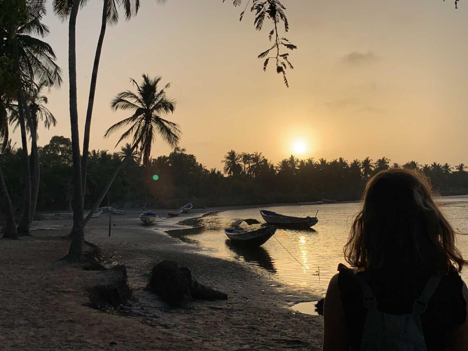 A student looks at small boats along the water's shore in Senegal.