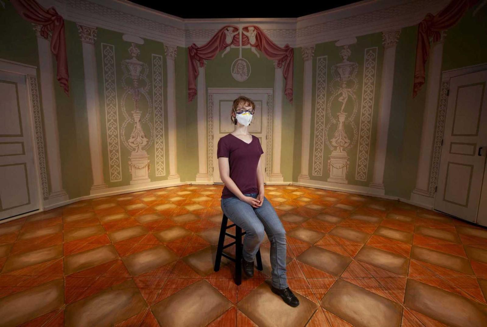 Claire Chamberlin, a junior, sits for a portrait in the Cloak Theater surrounded by the completed set for Molière Inspired. 
