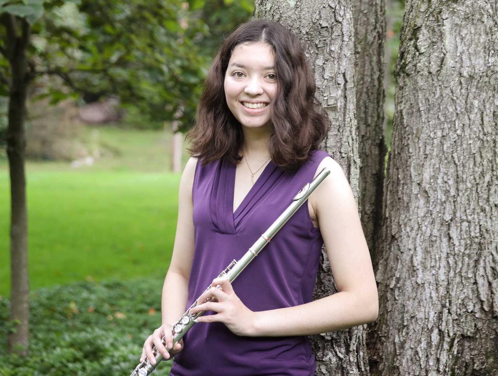 Cynthia Kaiser poses by a tree with her flute.