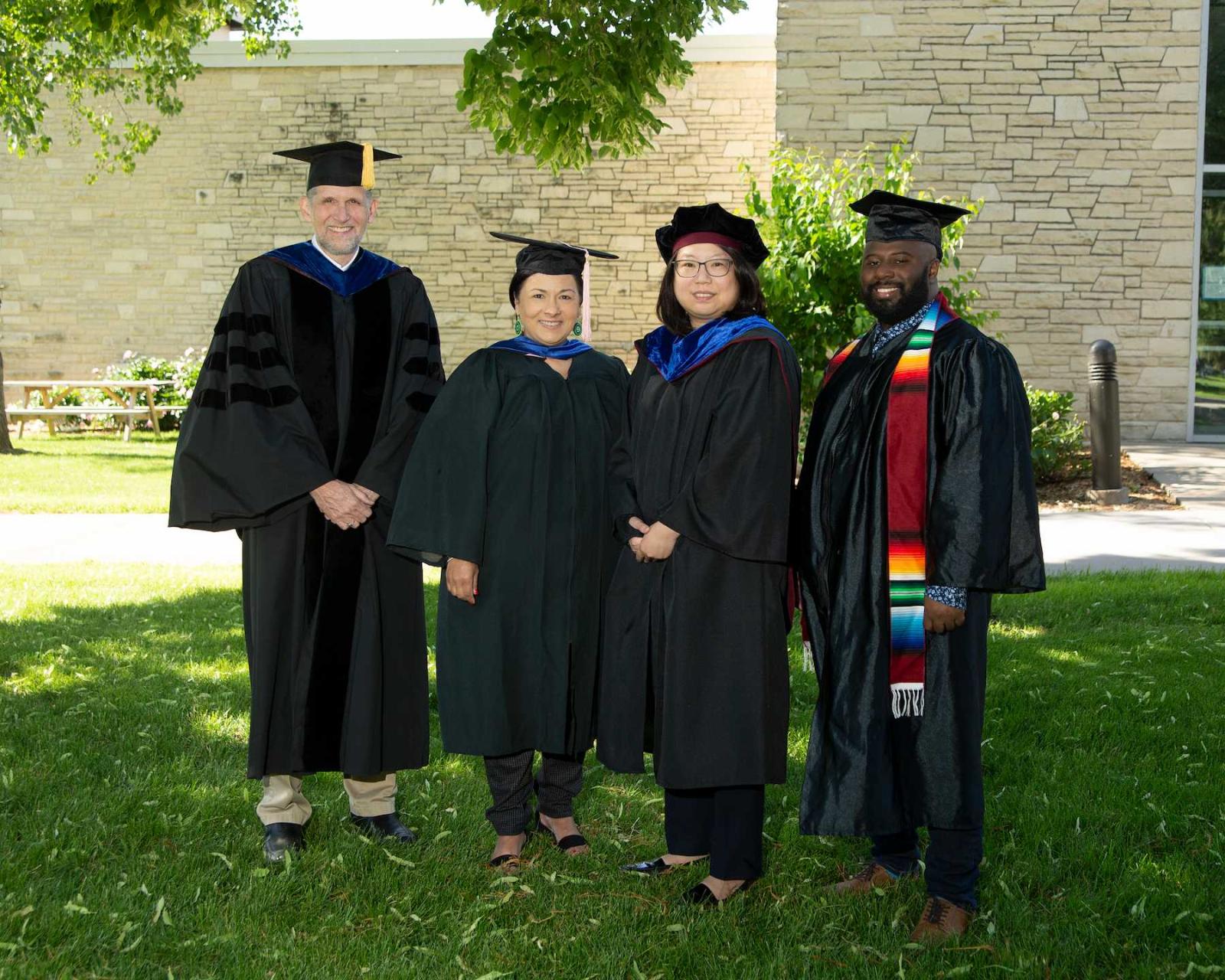 Faculty award winners, from left, 彼得游隼, Brigetta Miller, 南希·林, and Jesus Smith pose for a photo in their regalia.
