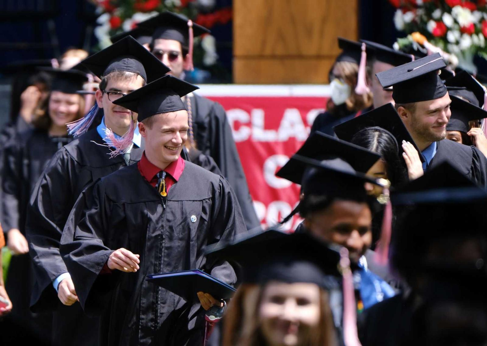Graduates walk to the 2022 Commencement ceremony in their caps and gowns.