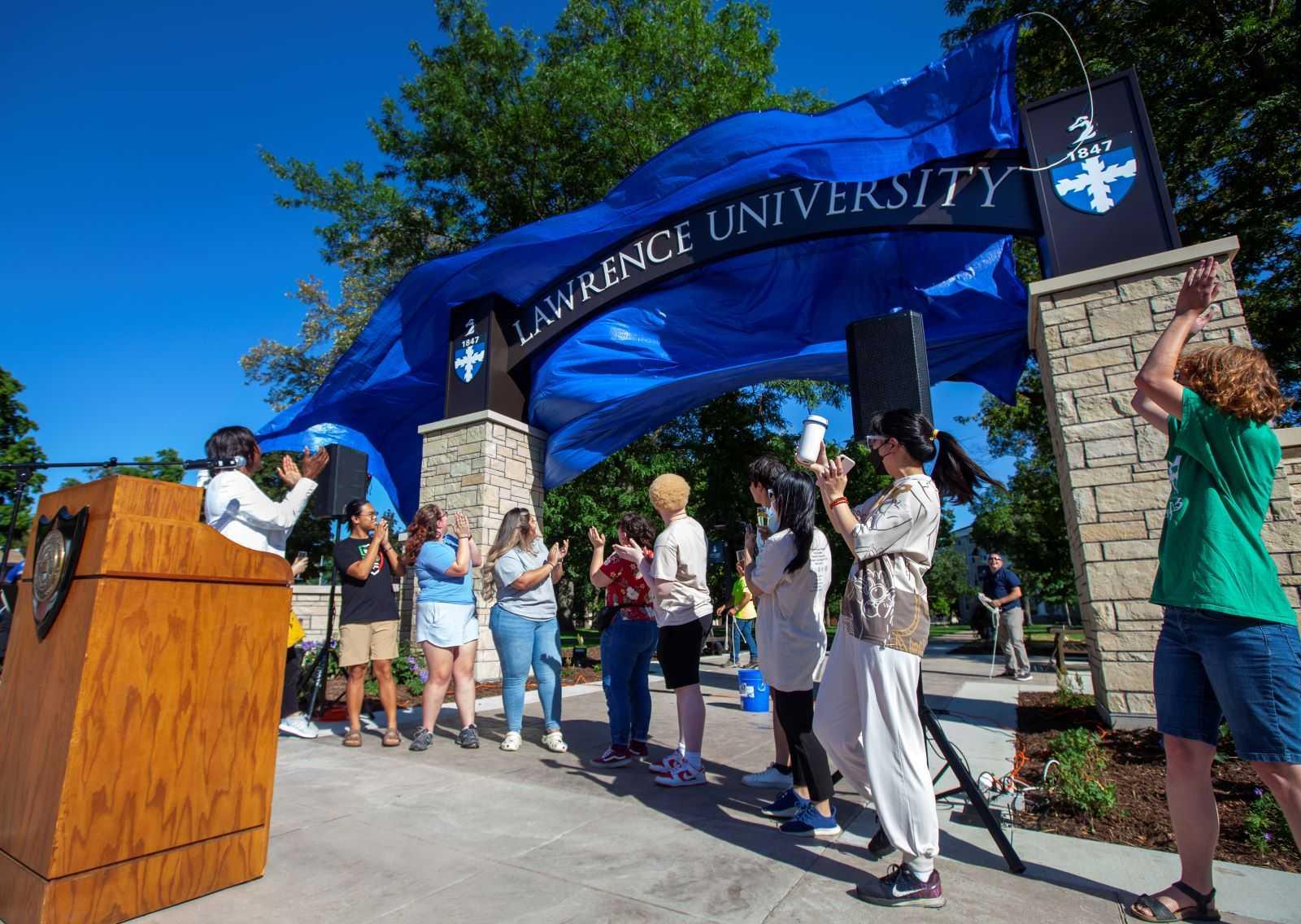 The blue tarp is pulled from the signage at the top of the Welcome Arch during the reveal on Thursday afternoon.