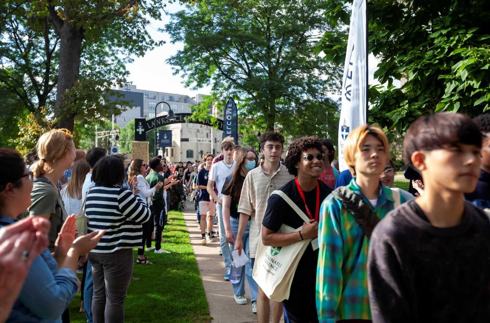 Lawrence community members line the walkway and applaud as incoming students walk through the arch.