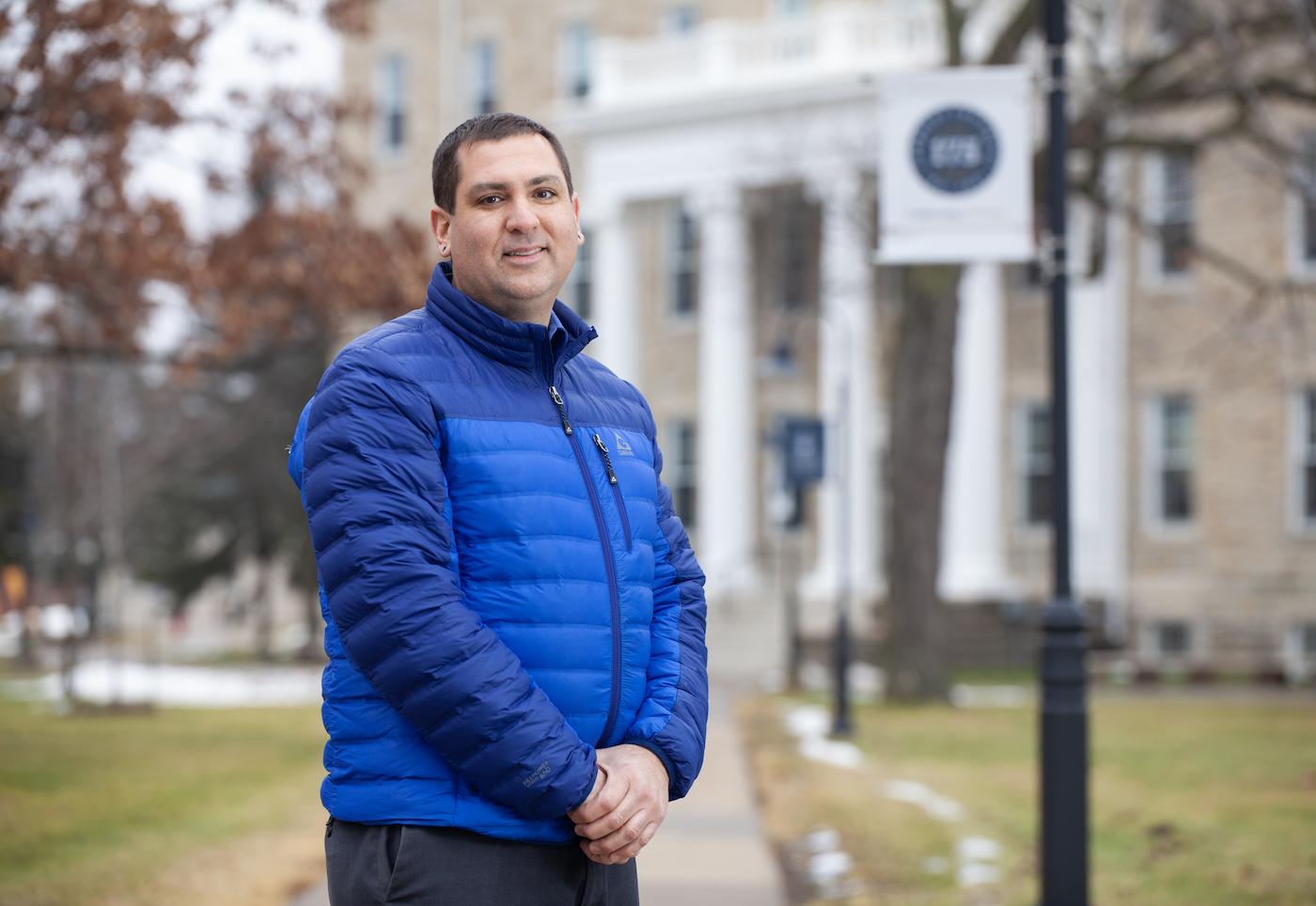 Brian Piasecki stands for a photo on the sidewalk leading to Main Hall.