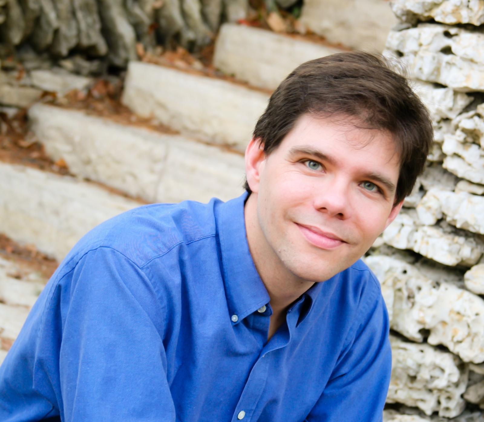Portrait of Brooke Joyce as he sits on steps made of stone.