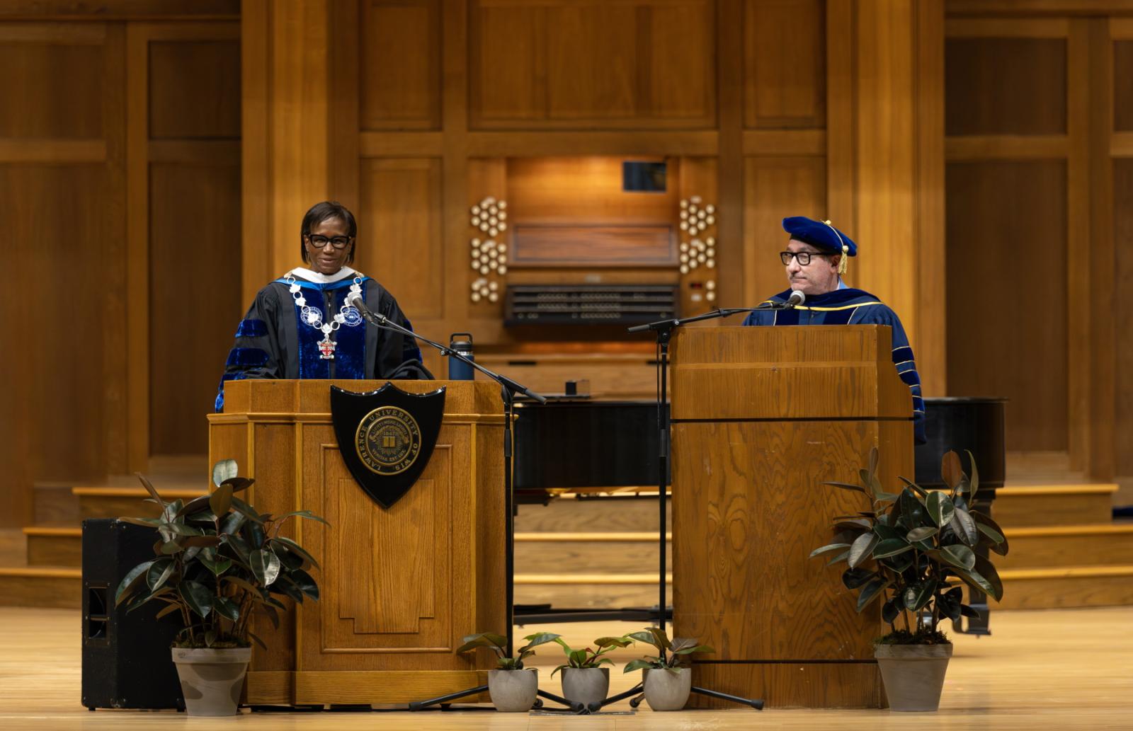 President Laurie A. Carter speaks at a podium on the stage of Memorial Chapel as Provost Peter Blitstein, at a second podium, looks on.