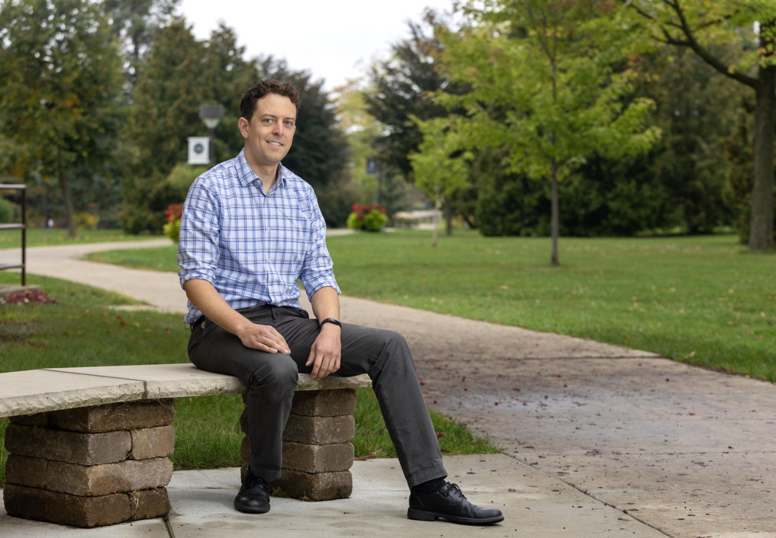 Graham Sazama sits on a bench outside of Main Hall.