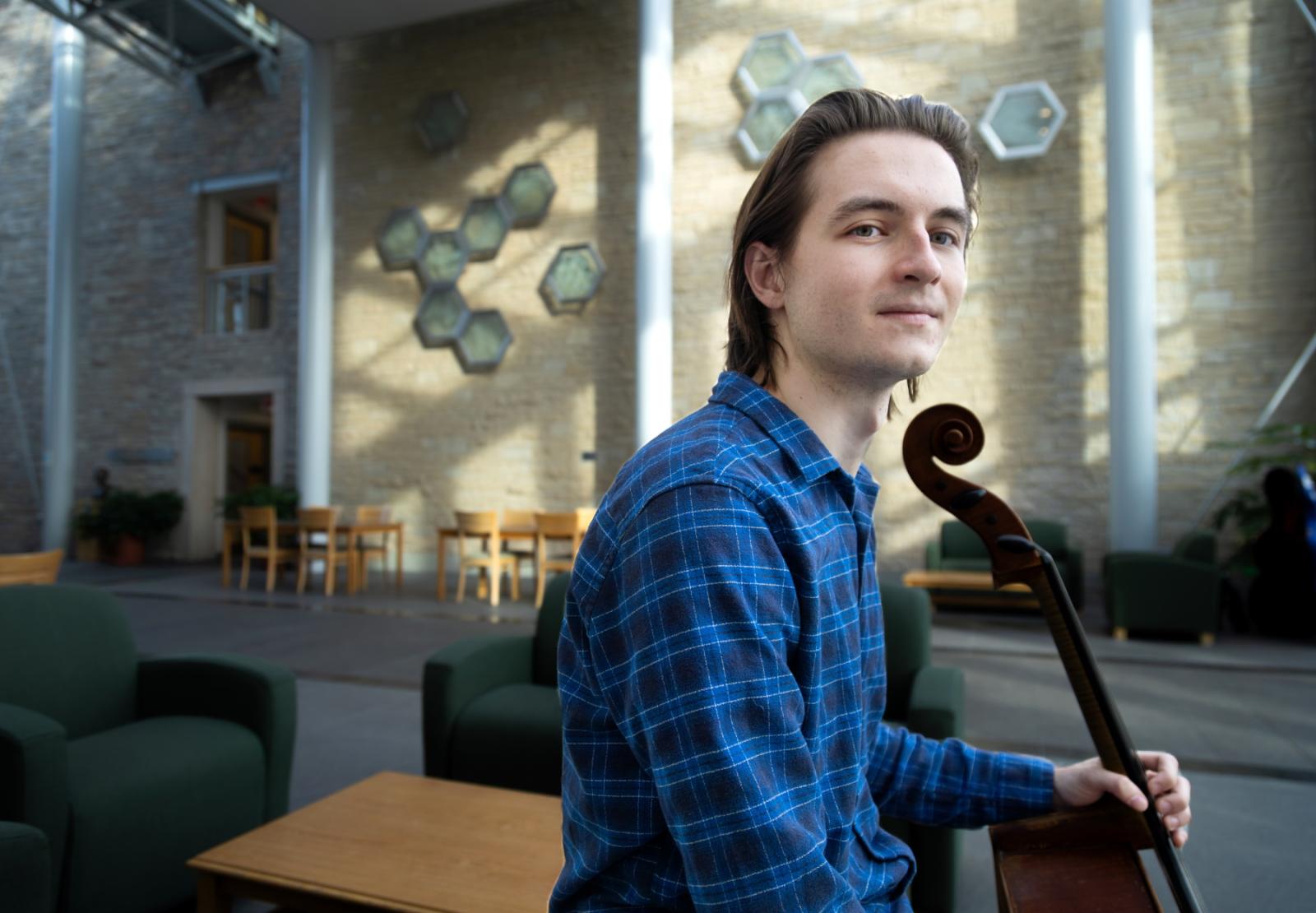 David Smith poses with his cello in the atrium that connects Steitz Hall of Science and Youngchild Hall of Science.