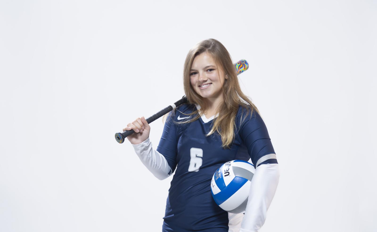 Taylor Hughes '25 holds a softball bat and volleyball during a Media Day photo shoot.