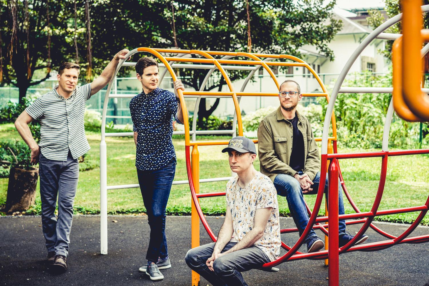 Kneebody poses for photo on outdoor playground.