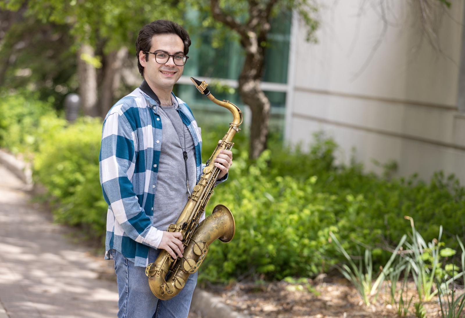 Eli Elder poses for a photo outdoors with his saxophone.