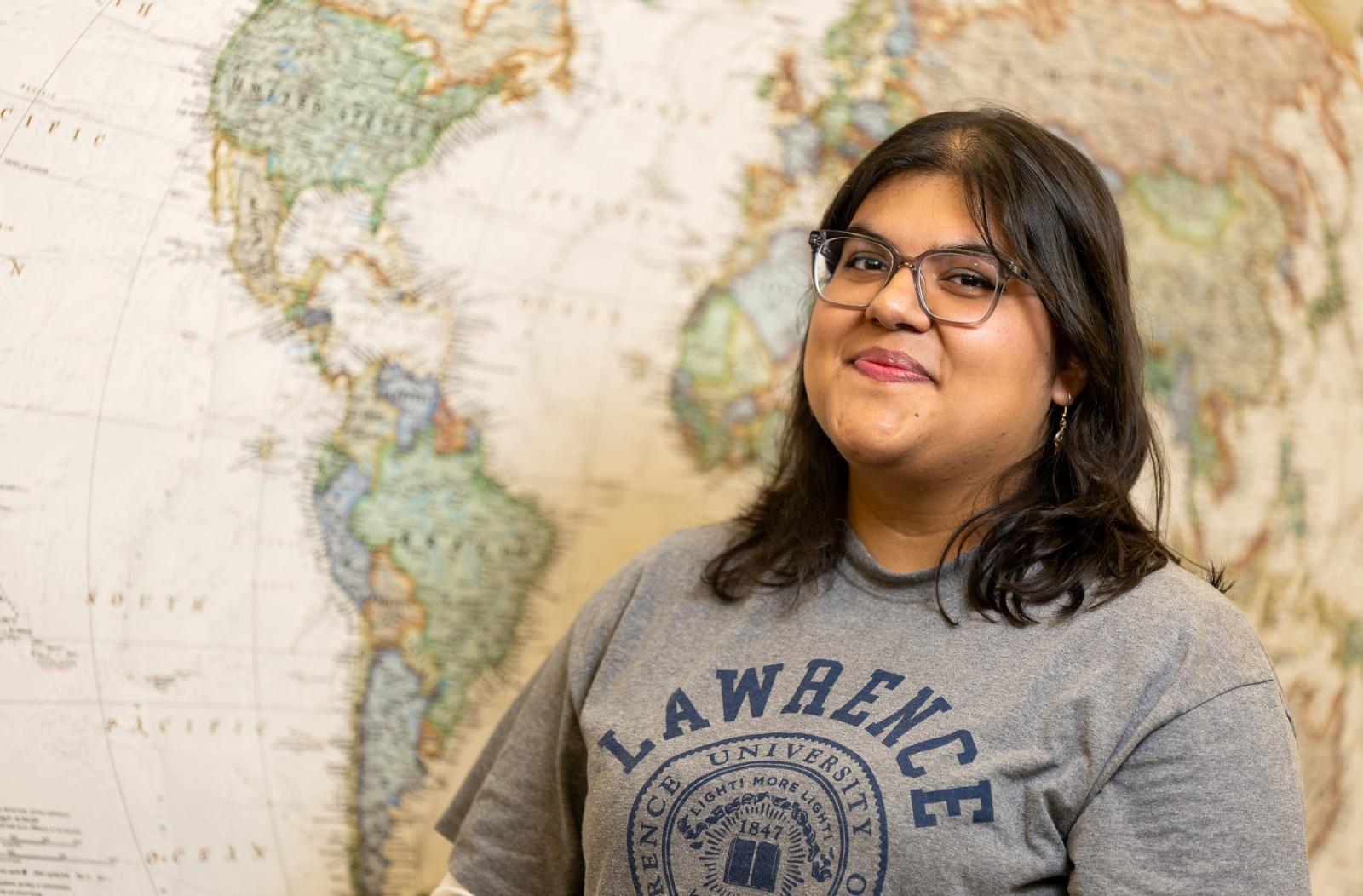 Paola Saldana Galvan poses for a photo in front of a world map.