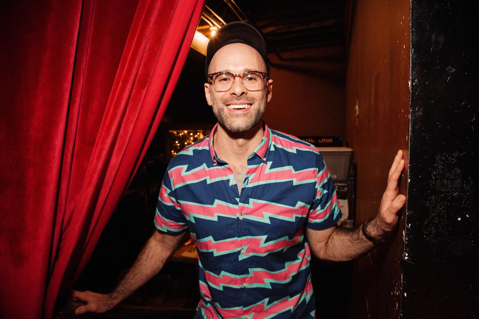 Asher Perlman looks out from behind a stage curtain.