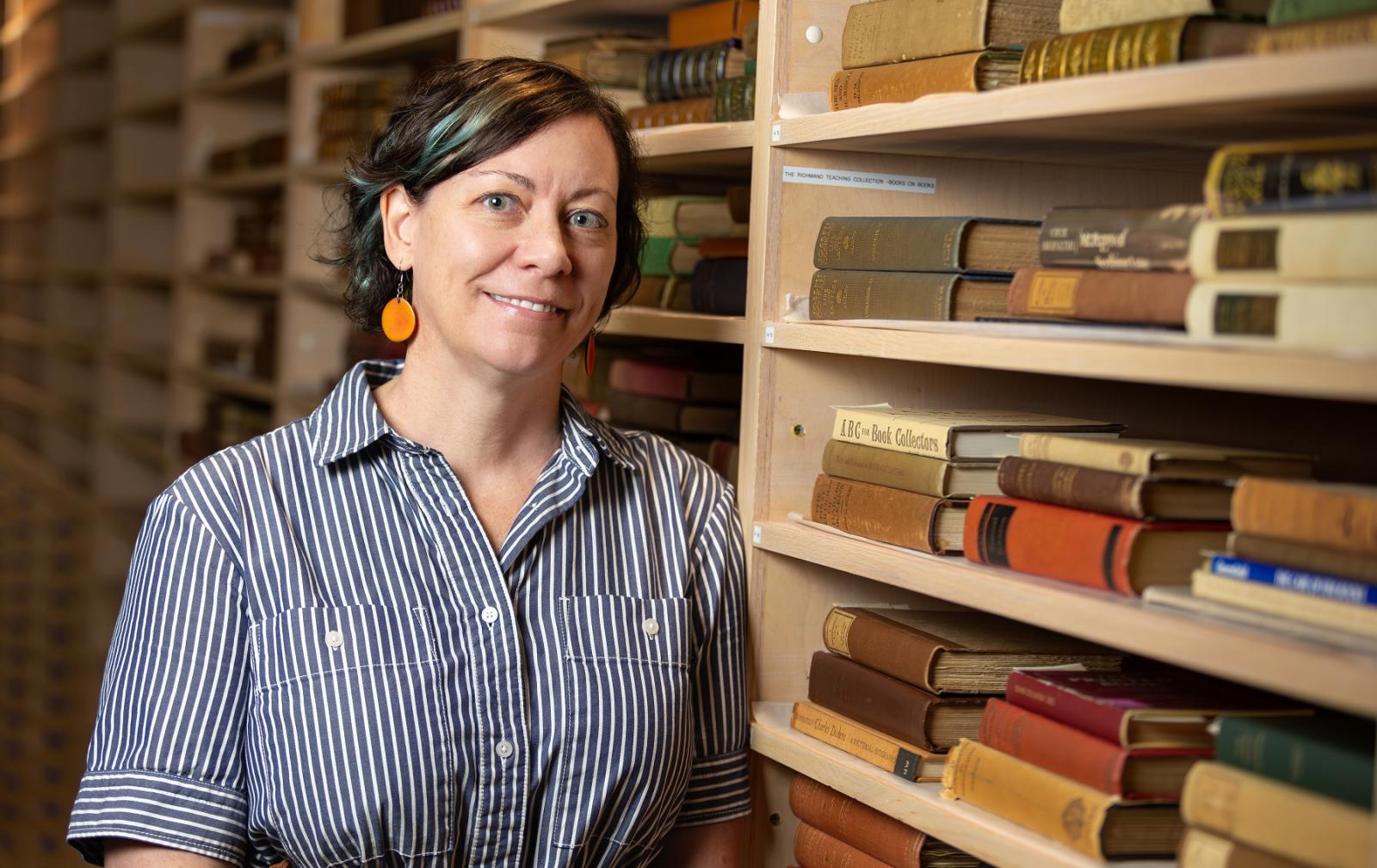 Beth Zinsli poses for a photo with books from the Richmond Rare Book Collection.