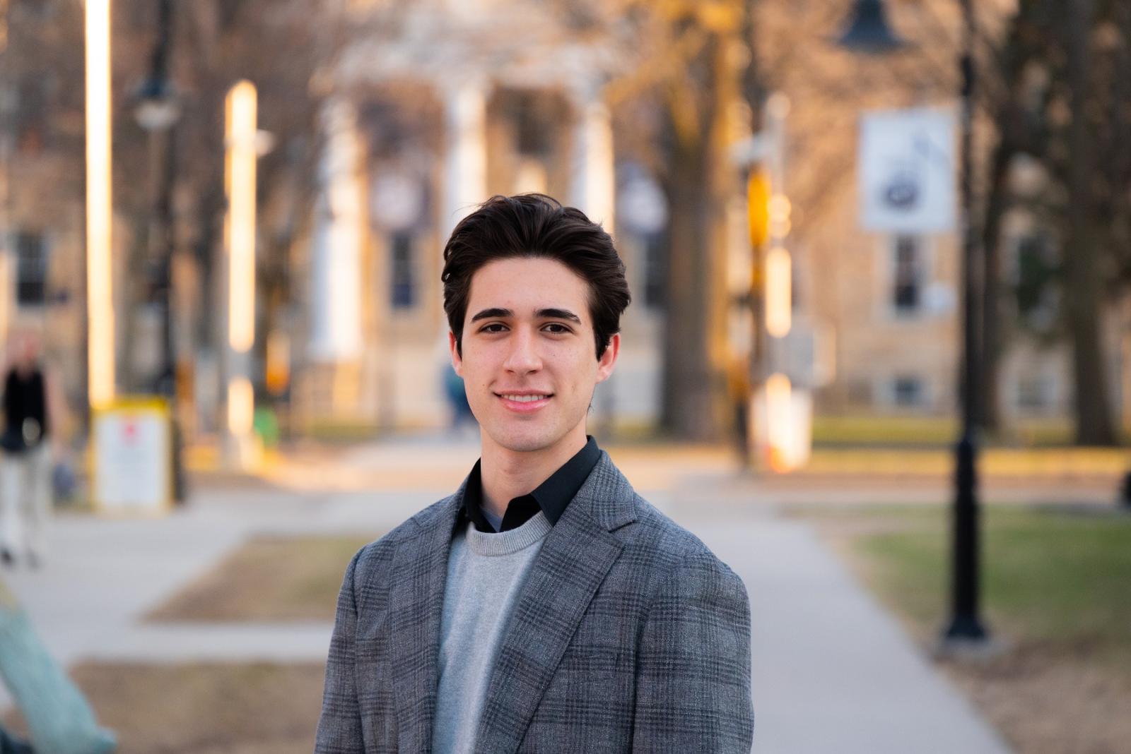 Adrian Stancil-Martin poses for a photo with Main Hall in the background. 