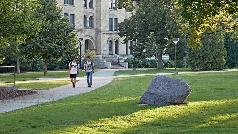 Students walking across Main Hall Green by the Rock