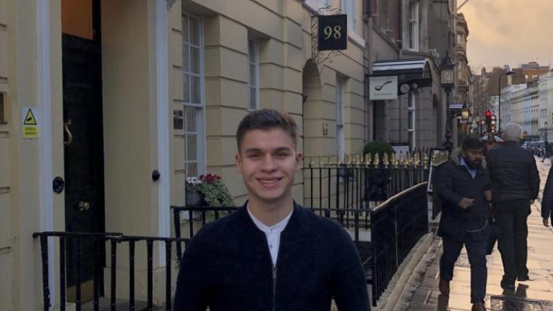 Andrea Arivella stands with his hands in his pockets on a UK sidewalk.