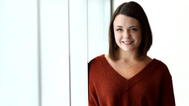 Martha Strawbridge poses against a white backdrop as she wears a red sweater.
