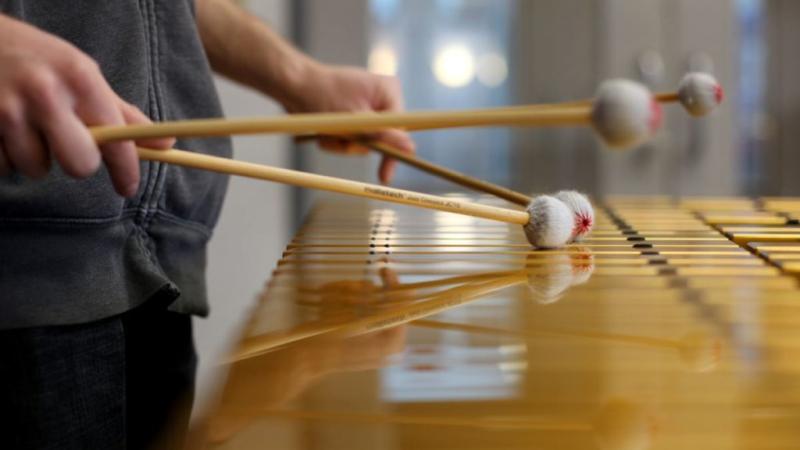 close up of the hands of a student playing the xylophone