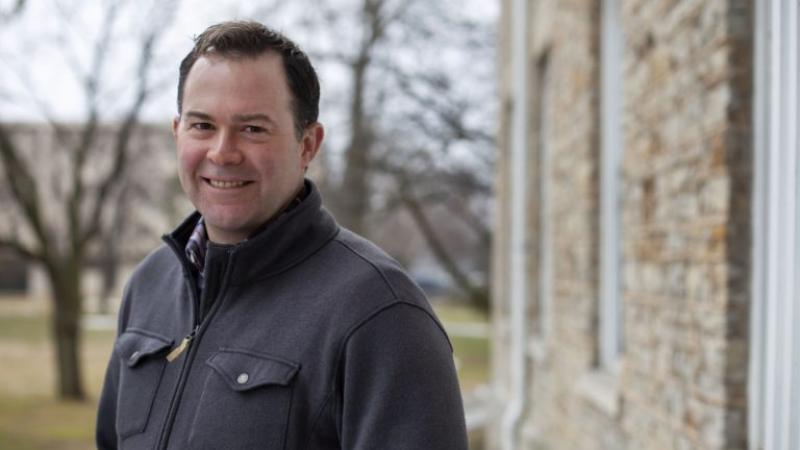 David McGylynn, wearing a grey jacket, smiles at the camera.