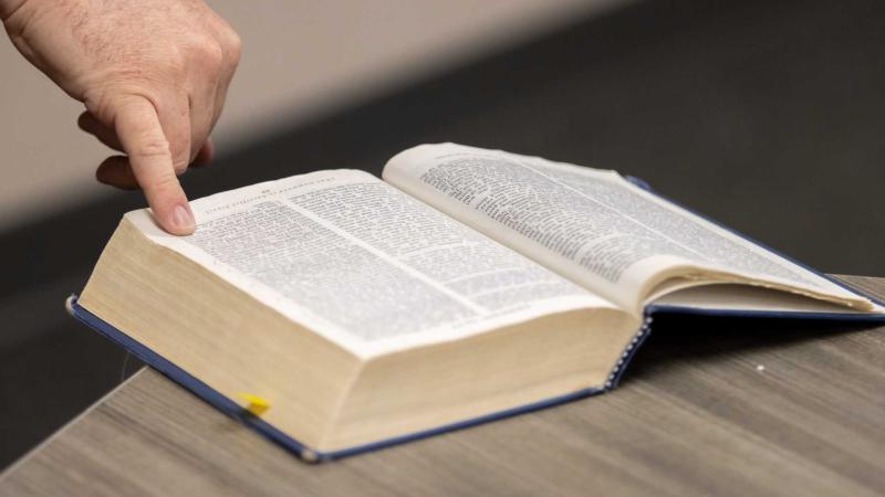 open bible with finger pointing to line on the page