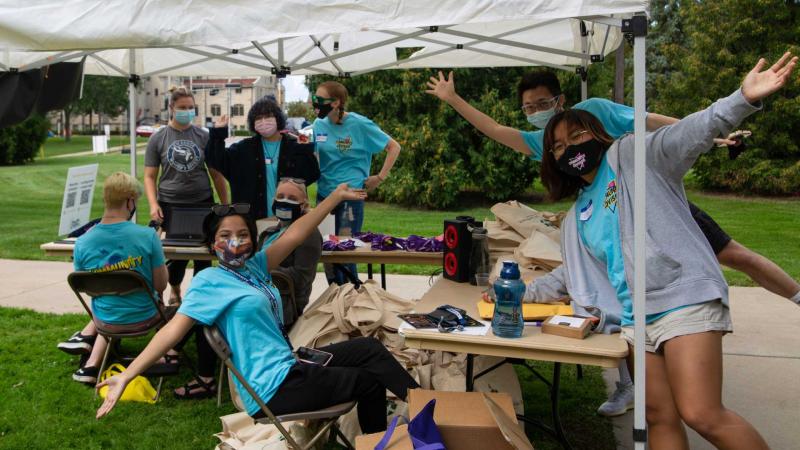 Group of community advisors pose for camera under white tent
