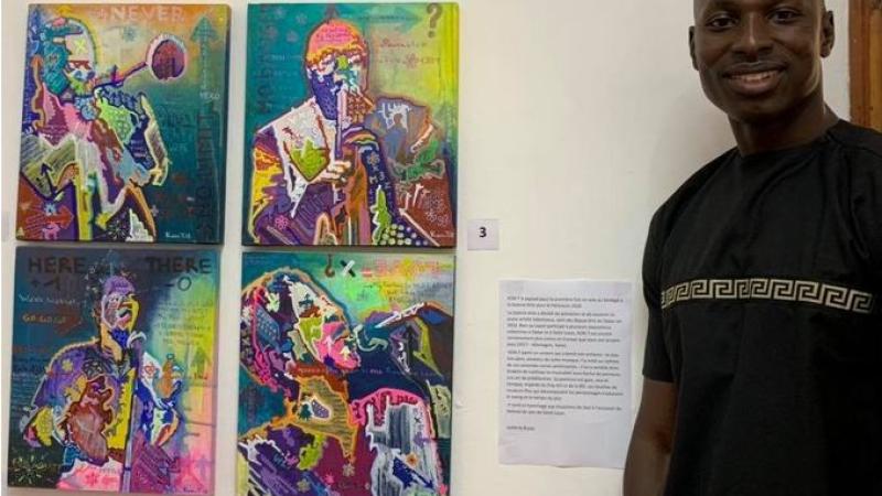 Man standing next to artwork hanging in exhibit.