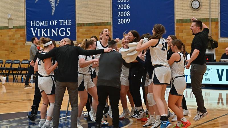 Players and coaches celebrate on the floor after the Vikings beat Ripon.