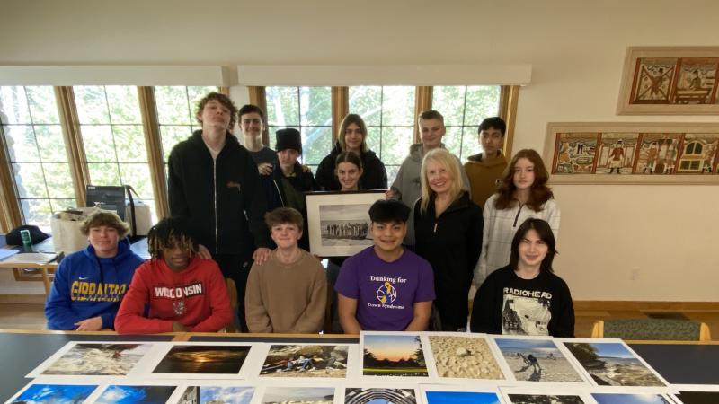 Students sit at a table with photos on it
