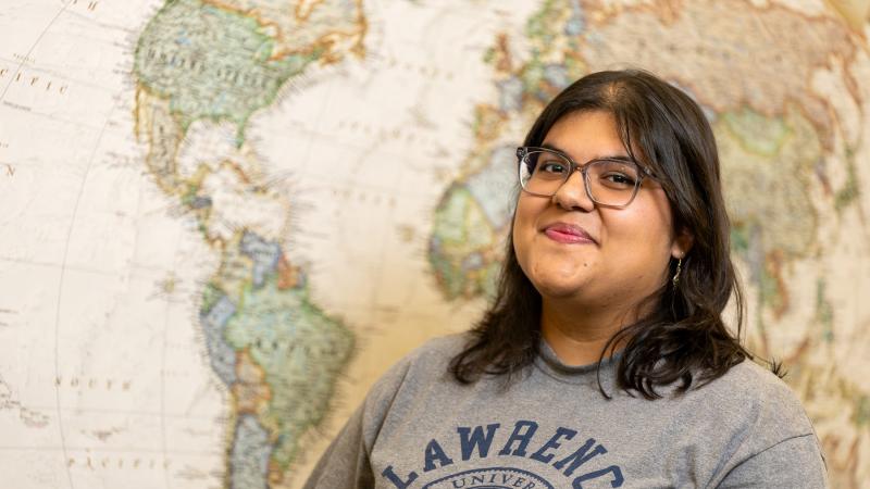 Paola Saldana Galvan poses for a photo in front of a world map.