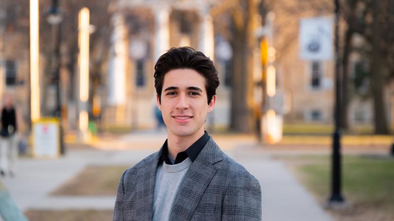 Adrian Stancil-Martin poses for a photo with Main Hall in the background. 