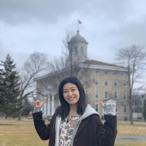 Student posing in front of Main Hall on overcast fall afternoon