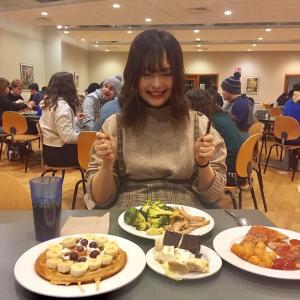 Student with fork and knife smiling at large plates of food.